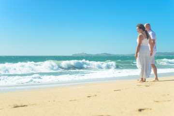 Fototapeta na wymiar Young romantic couple walking on the beach holding hands
