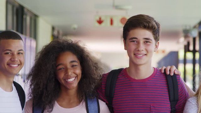 Teenage classmates standing in high school hallway, close up