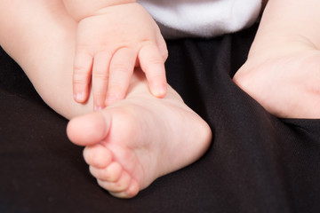 little foot and the hand of a new baby newborn on black background