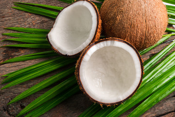 Coconut halves and green leaf on old wood background. Top view with copyspace