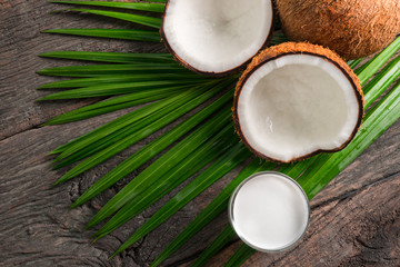 Coconut halves and green leaf on old wood background. Top view with copyspace