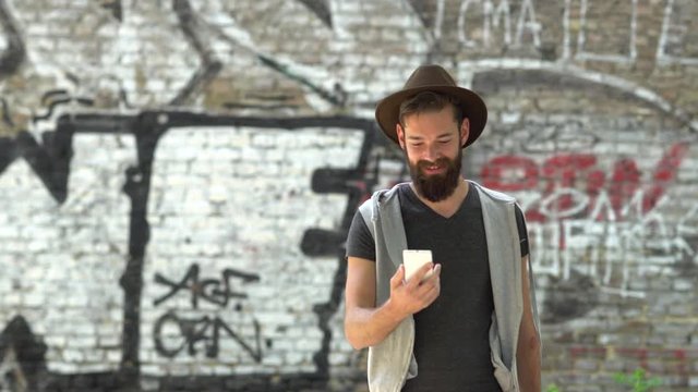 Handsome bearded hipster walking and laughing during a video call