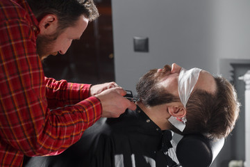Barber making beard haircut using shaver