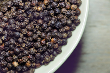 close up of black pepper in white bowl.