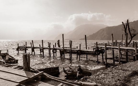 Rural landscape with old rickety wooden piers out into Lake Atitlan in Guatemala on the shore in Panajachel village with highlands in the background. 