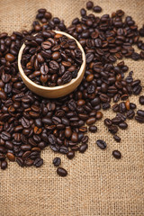 Wooden bowl with roasted coffee beans on rustic background.