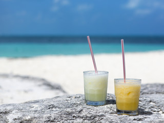 Colorful drink on the beach. Sunny and hot day. Refreshing cold cocktail with a straw. Focus point on the drink.