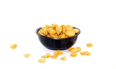 Dried beans overflow from a black plastic cup on white background.