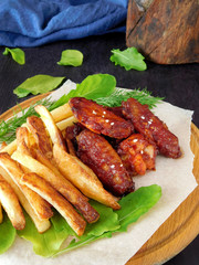 French fries and grilled chicken wings on the green salad