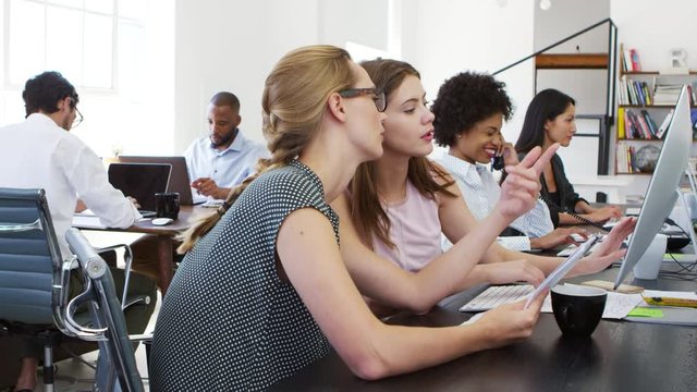 Woman training new female employee in an open plan office