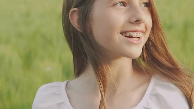 Happy young girl walks and poses in the green wheatfield. Slowly
