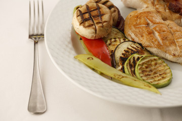 Chicken with bacon and grilled vegetables arranged on a plate, Traditional dish in elegant setting, Selective focus with soft light