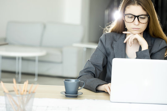 Serious young woman using laptop computer