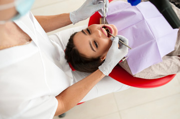 Beautiful girl treats teeth in dentistry.