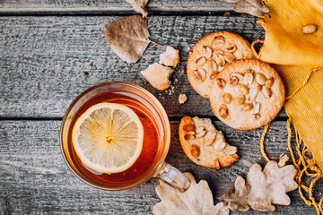 Cozy autumn breakfast with hot cup of lemon tea, Peanut biscuit cookies on wooden table. Seasonal relax concept. Top view, copy space