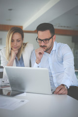 Obraz premium Two business people sitting on office and using credit card. Business people checking credit card on laptop.