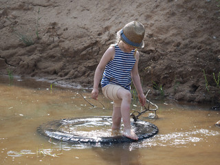 Happy little girl playing in a big puddle of sand quarry