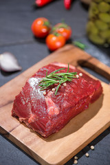 Raw beef on a cutting board  with spices and ingredients for cooking.