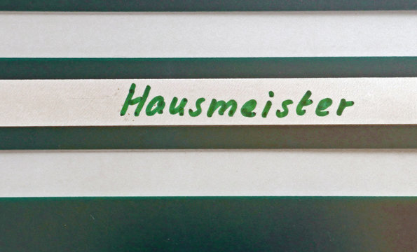 Grau-weiß gestreiftes Schild mit der handschriftlichen Aufschrift "Hausmeister"