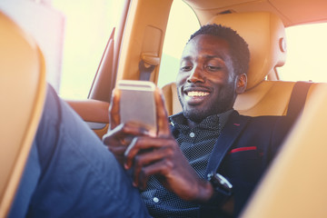  Black male using a smart phone in a car.