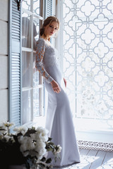 Young blonde bride woman in a light blue wedding dress, fashion beauty portrait in interior