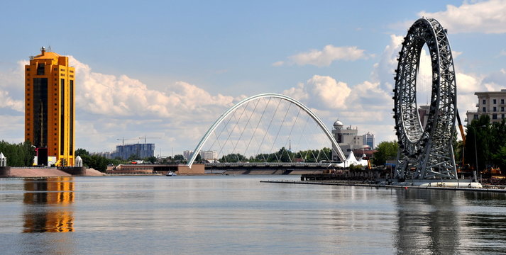 Blick auf den Fluss Ischim mit Hochhaus und moderner Bogenbr&uuml;cke