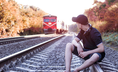 Teenager with headphones listens to music on the railway tracks