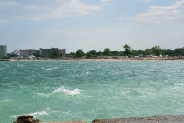 Neptun, Romania - July 8, 2017: The Black Sea changes colour to turquoise due to a natural but very rare phenomenon caused by microorganism. In the background is the beach resort in Neptun, Romania © Florin