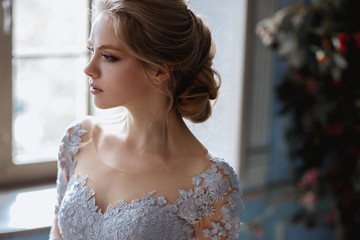 Young blonde bride woman in a light blue wedding dress, fashion beauty portrait in interior