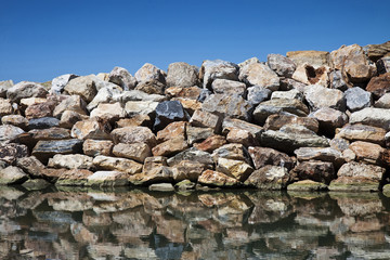 Rock and stone wall to protection from the waves against a blue sky