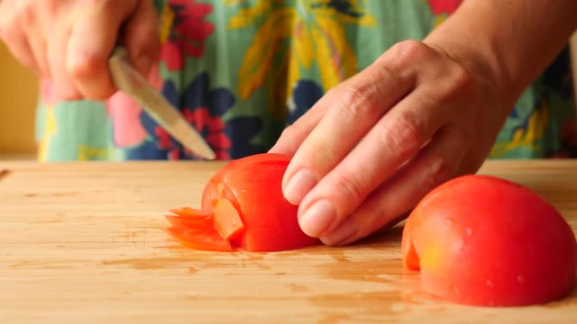 Woman's hands with a knife cut on a wooden board. 4k. Slow motion