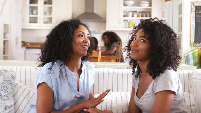 Mother Talking With Teenage Daughter Sitting On Sofa Together