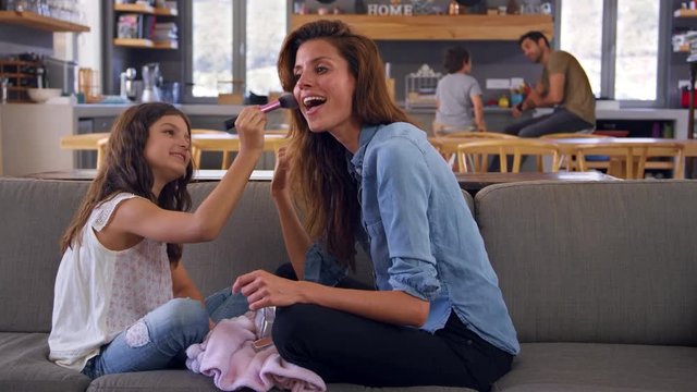 Daughter Sitting On Sofa At Putting Make Up On Mother