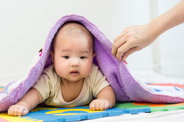 Portrait of a little adorable infant baby girl with blanket lying on the tummy on colorful eva foam indoors