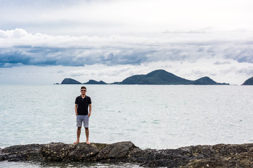 Fototapeta na wymiar Portrait of a man with standing on the rock with sea, mountain and cloud