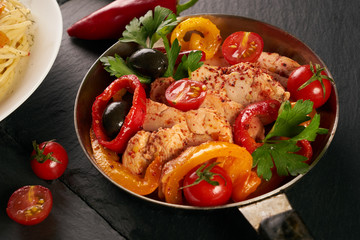Fried chicken with vegetables on the pan and Italian pasta with a parmesan cheese basil olives paprica and tomatoes on a plate. Healthy food copncept. Top view copy space.