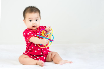 Portrait of adorable infant baby girl sitting on the bed with bites toy