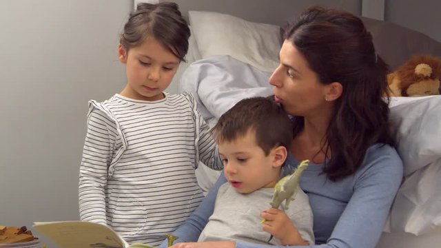 Mother Reading Story To Children In Their Bedroom