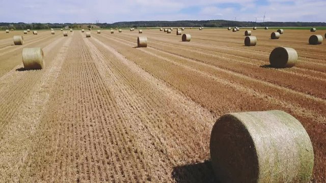 drone backward flight over field with hay bales.