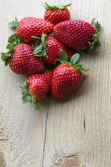 Small pile of big fresh strawberries are on the wooden background