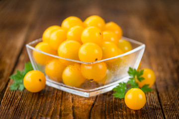 Yellow Tomatoes on wooden background; selective focus