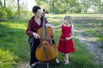 Music lesson on the cello. Grandmother and granddaughter 