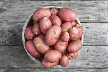 Fresh potato on a old wooden texture. Top view.