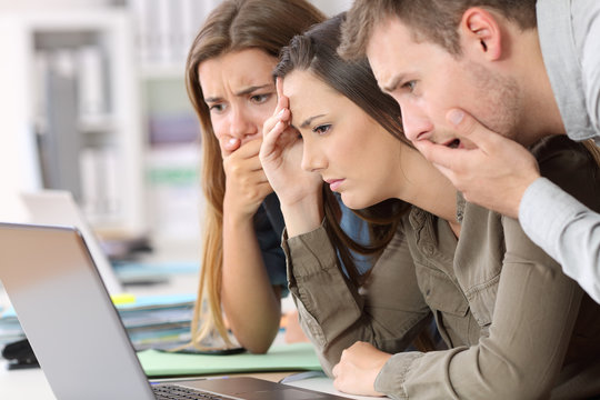 Worried employees reading bad news on line
