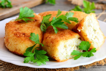 Vegetable cakes with egg stuffing on a white plate. Cakes cooked from cauliflower and potatoes and stuffed with boiled sliced eggs. Rustic style. Closeup