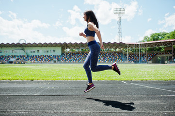 Fototapeta premium Portrait of a strong fit girl in sportswear running in the stadium.