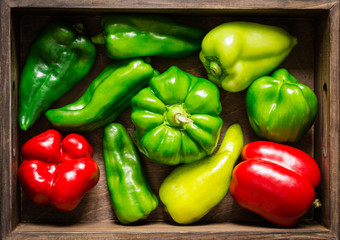 Wooden box with different red and green bell peppers closeup