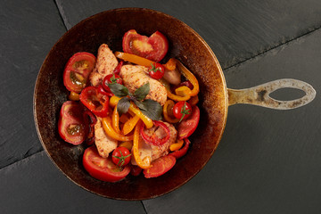 Fresh Vegetables and Chicken. Fried chicken fillet and vegetables tomato garlic onion bell pepper basil green and spicy seasoning in cooking pan. Healthy dinner at Restaurant. Closeup, top view