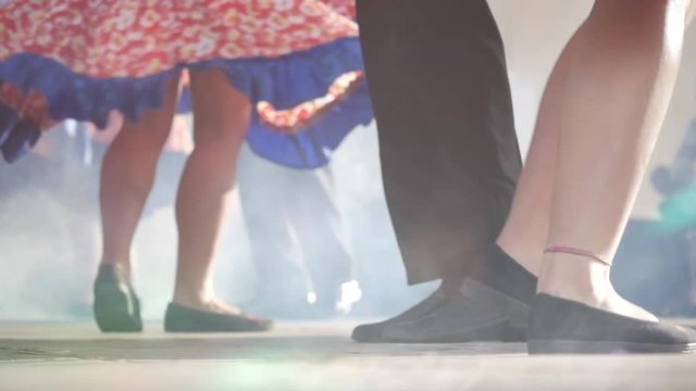 Teenager dancers performing a folklore dance on stage. Detail of legs and feet. Slow motion	