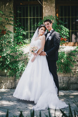Naklejka premium Beautiful bride and groom posing in a yard of a castle on their wedding day